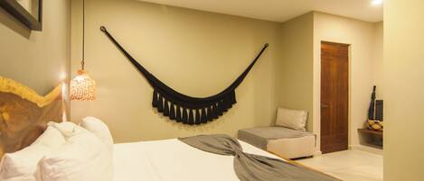 A bedroom with a bed, a hanging chair, a wooden door, and a small shelf with a vase.