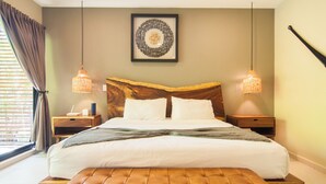 Ein ordentlich eingerichtetes Schlafzimmer mit einem großen Bett, zwei Nachttischen, einer hölzernen Bank und einem gerahmten Kunstwerk an der Wand.