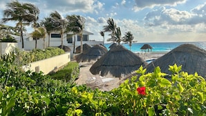 Ein Resort mit Strohdachschirmen, Palmen und einem Poolbereich.