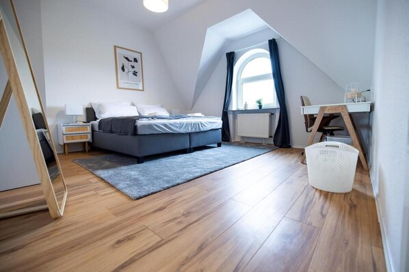 A modern bedroom with a bed, bedside table, and a desk with a chair.