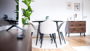 Uma sala de jantar moderna com mesa redonda, cadeiras brancas e um armário de madeira.