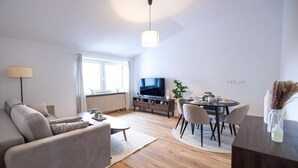 Uma sala de estar moderna com sofá, mesa de centro, televisão, mesa de jantar e cadeiras.