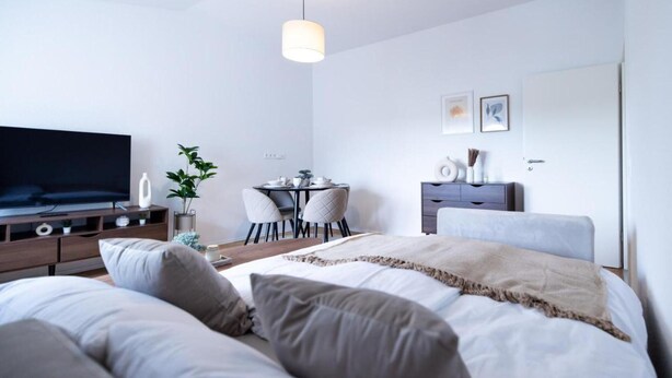 Quarto moderno com uma cama grande, uma televisão, uma escrivaninha e uma cadeira.