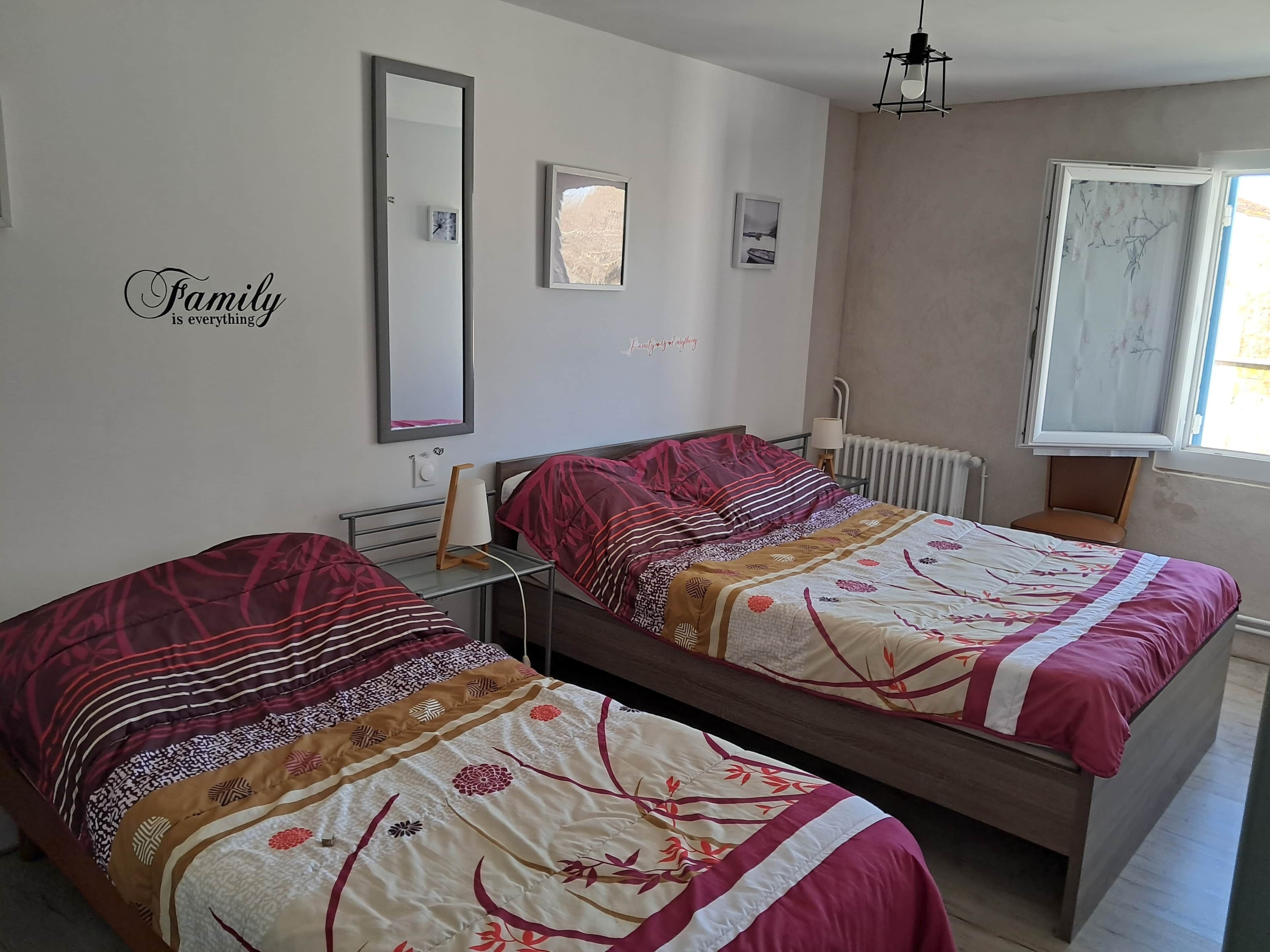 Une chambre avec deux lits, un miroir, une horloge et une fenêtre donnant sur un paysage agréable.