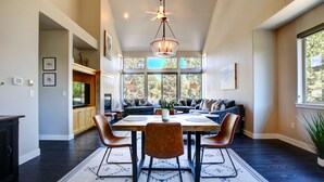 A spacious dining area with a high ceiling, large windows, and a chandelier. - Beautiful Eagle Crest Condo, HOT TUB, 2 Bed/2 Bath (Redmond)