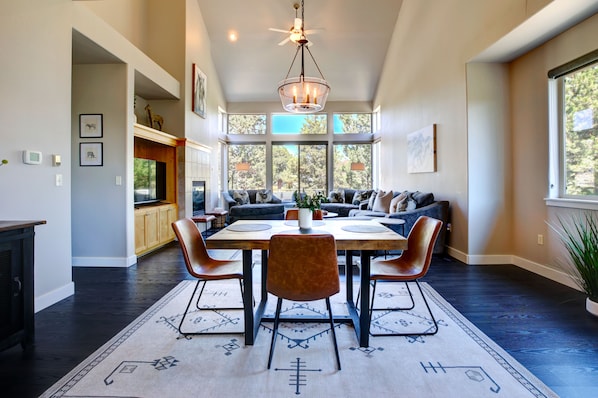 A spacious dining area with a high ceiling, large windows, and a chandelier.