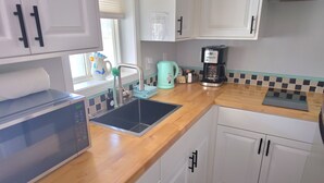 A kitchen with a microwave, sink, coffee maker, and cabinets. - Blue Octopus #2 Beach Access (Rockaway Beach)