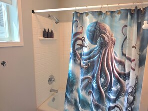 A bathroom with a shower curtain featuring an octopus design, a bathtub, and a window with blinds. - Blue Octopus #2 Beach Access (Rockaway Beach)