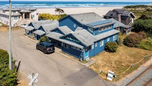 A coastal hotel with a prominent blue building named "The Blue Octopus," situated near a beach and railroad crossing. - Blue Octopus #2 Beach Access (Rockaway Beach)