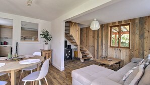 A spacious living area with a wooden staircase, a dining table with chairs, and a sofa. - Chez Jacotte (Gérardmer)