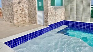 Um edifício moderno com piscina, fachada de pedra e uma porta.