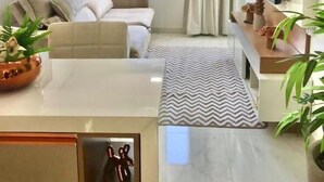 Sala de estar moderna com sofá, televisão e plantas decorativas.