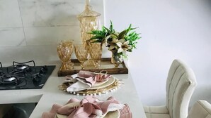 Uma mesa de jantar posta com pratos, guardanapos e um arranjo central.