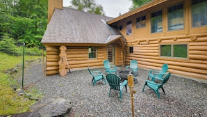 Une cabane en rondins avec un patio en gravier, un espace salon extérieur et un foyer.