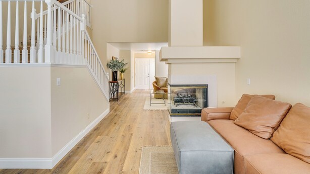 A spacious living area with a staircase, a fireplace, and a leather sofa. - Luxe 3BR Executive Home w/ Pool, Office & Patio (Las Vegas)