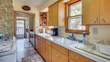 Une cuisine avec des meubles de rangement en bois, un évier, une cuisinière et une fenêtre.