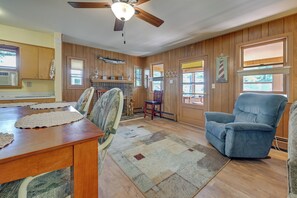 A dining area with a wooden table, chairs, a ceiling fan, and a fireplace. - 4-Season Anglers Cabin At Shawano Lake w/ Views! (Shawano)