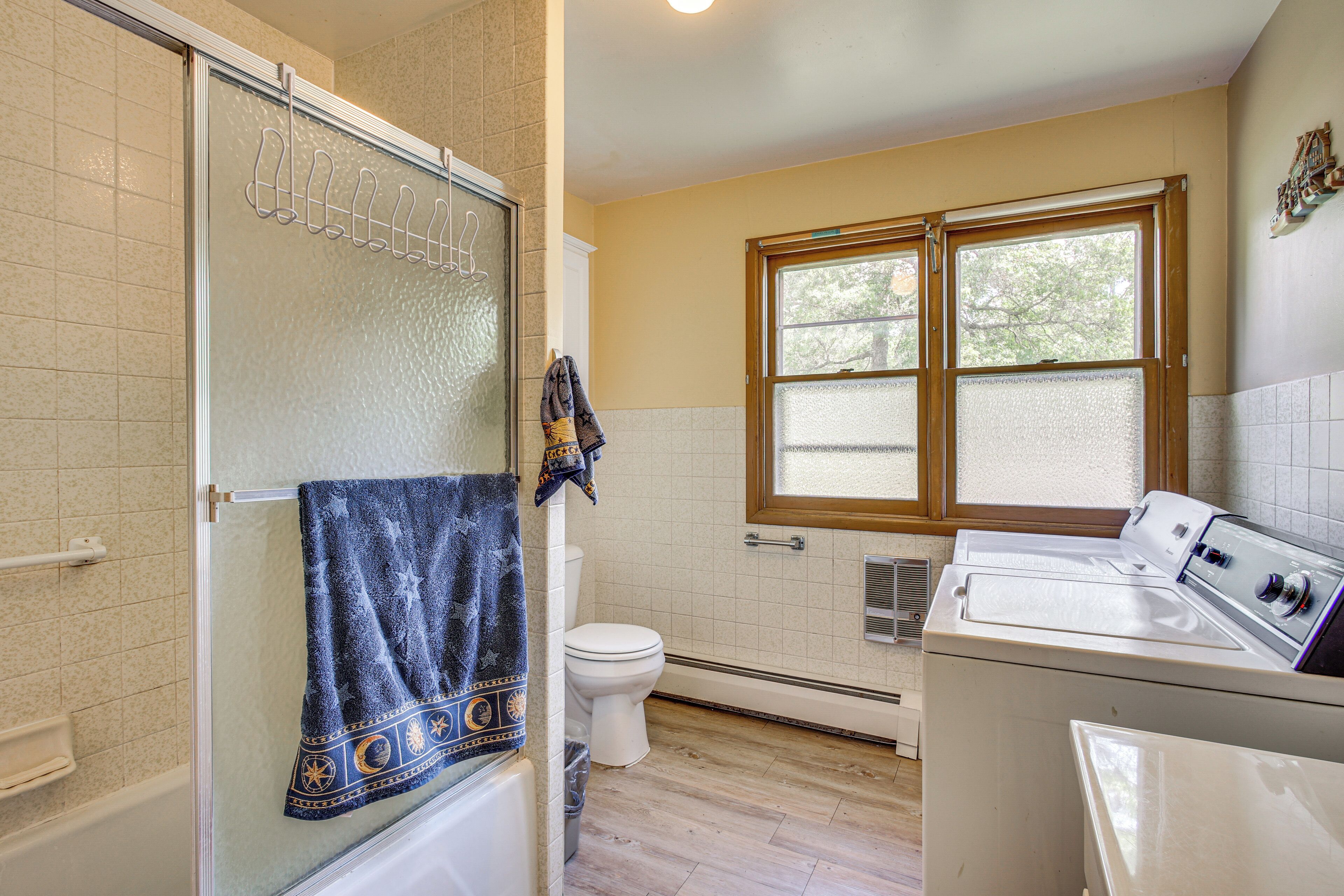 A bathroom with a shower, toilet, and a window.