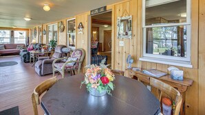 Une pièce chaleureuse avec un décor intérieur en bois, une table à manger avec des chaises, un canapé et une grande fenêtre.