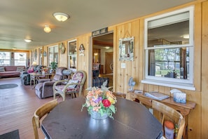 Una habitación acogedora con detalles de madera, una mesa de comedor con sillas, un sofá y un ventanal grande.