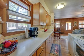 A kitchen with wooden cabinets, a coffee maker, a fruit basket, and a stove. - 4-Season Anglers Cabin At Shawano Lake w/ Views! (Shawano)