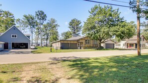 A residential street with houses, a clear sky, and a grassy area. - 4-Season Anglers Cabin At Shawano Lake w/ Views! (Shawano)