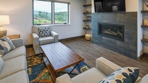 A living room with a fireplace, a sofa set, a coffee table, and a large window with a view of the outdoors. - Steamboat Springs Apt w/ Views, 15 Mi to Skiing! (Steamboat Springs)