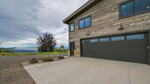 A modern two-story house with a garage, a driveway, and a view of a lake. - Steamboat Springs Apt w/ Views, 15 Mi to Skiing! (Steamboat Springs)
