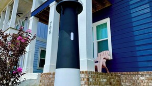 A lighthouse on a pedestal in front of a two-story building with a balcony. - Downtown retreat by the Bay, Bruce Beach, Blue Angels,  parades & fish market!  (Pensacola)