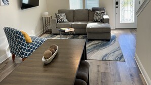A modern living room with a dining table, sofa, and a ceiling fan. - Downtown retreat by the Bay, Bruce Beach, Blue Angels,  parades & fish market!  (Pensacola)