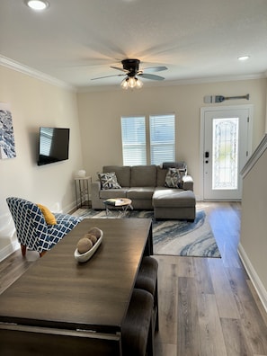 Relax in this stylish living room with a dining table, comfortable sofa, and flat-screen TV.