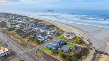 An aerial view of a coastal town with houses near the beach, a road, and a railway track.