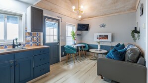 Een compacte keuken met een spoelbak, kastjes en een eethoek met een tafel en stoelen.
