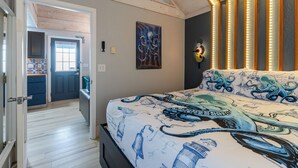 Een slaapkamer met een bed met octopusbeddengoed, een schilderij aan de muur en een modern hoofdeinde met LED-verlichting.