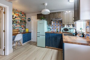Une cuisine équipée d’un réfrigérateur, d’un four à micro-ondes, d’un évier et agrémentée d’un mur décoratif.