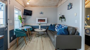 Een woonkamer met een bank, twee stoelen, een televisie en een open haard.