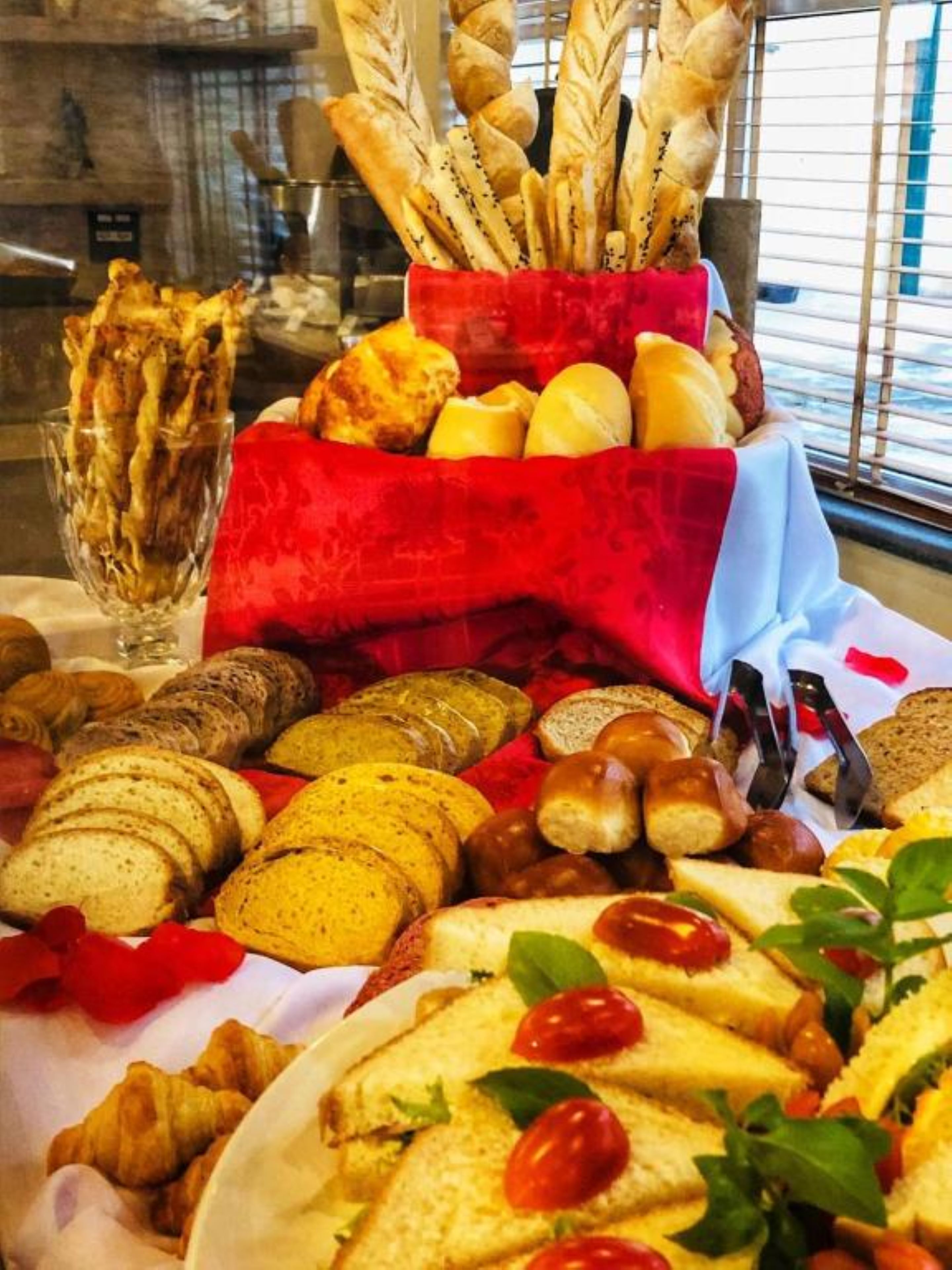 A variety of breads and pastries displayed on a table with a red cloth.
