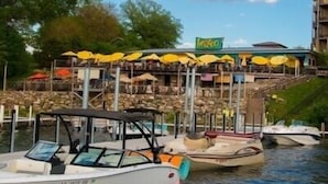 Ein Restaurant am Wasserufer mit Terrassenplätzen und angestaubten Booten in der Nähe.