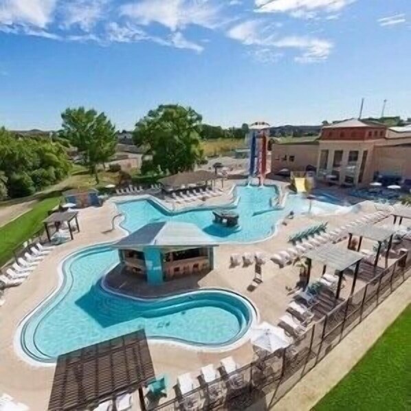 A swimming pool with a wavy design, surrounded by lounge chairs and a small building. - PRIME LOCATION AT BRIDGES BAY RESORT!!! (Arnolds Park)
