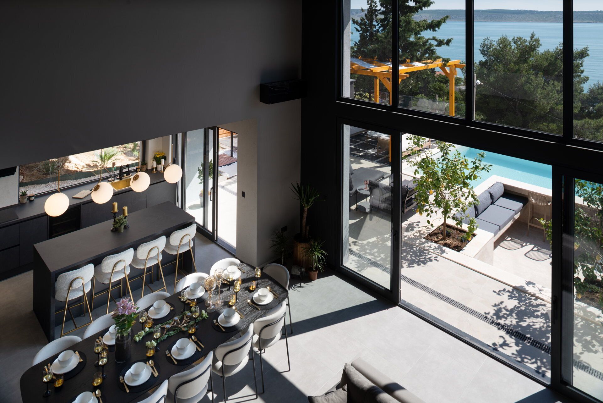 Ein moderner Essbereich mit einem großen Fenster mit Blick auf einen Pool und Sitzgelegenheiten im Freien.