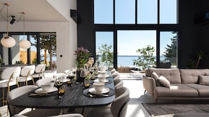 Zona pranzo moderna con un tavolo grande apparecchiato per sei, con vista panoramica sul mare.