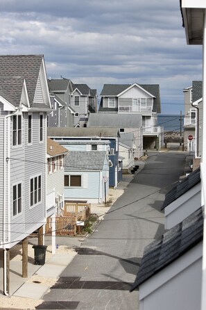 A residential street with houses, a stop sign, and a view of the ocean.