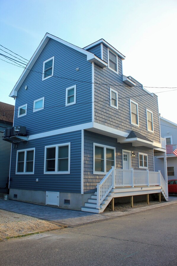 A two-story house with a front porch and a small staircase leading to the entrance.