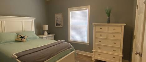 Un dormitorio con cama, cómoda, mesita de noche y ventilador de techo.