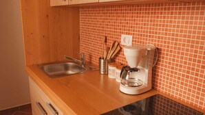 Une cuisine dotée d’un plan de travail en bois, d’un évier en acier inoxydable, d’une machine à café et d’un dosseret carrelé.