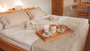 Un lit bien fait, avec un plateau contenant des articles de toilette, notamment un pot de crème, un verre d’eau et une cuillère.