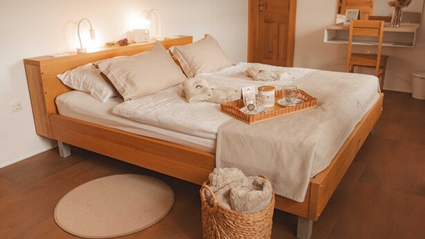 Un lit bien fait, avec un cadre en bois, une table de chevet avec une lampe et un petit tapis rond sur le sol.
