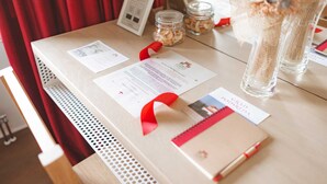Una mesa con un certificado, una cinta roja, una libreta y un bolígrafo.