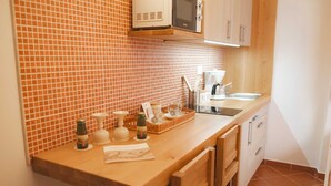 Una cocina con encimera de madera, microondas, lavabo y salpicadero azulejado.