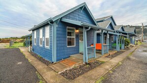 Ein blaues Gebäude mit Veranda, Holzterrasse und Schotterauffahrt.